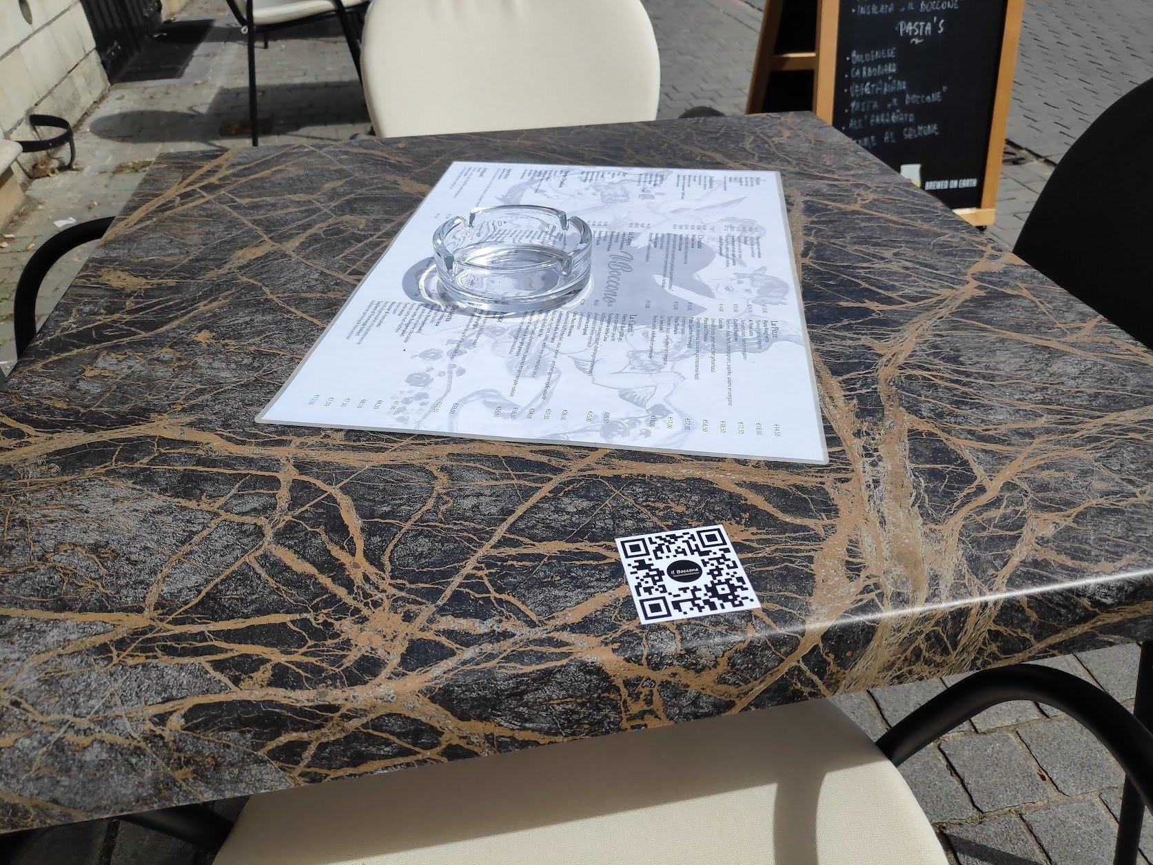 Il Boccone QR-sticker op een terrastafel naast de menukaart.