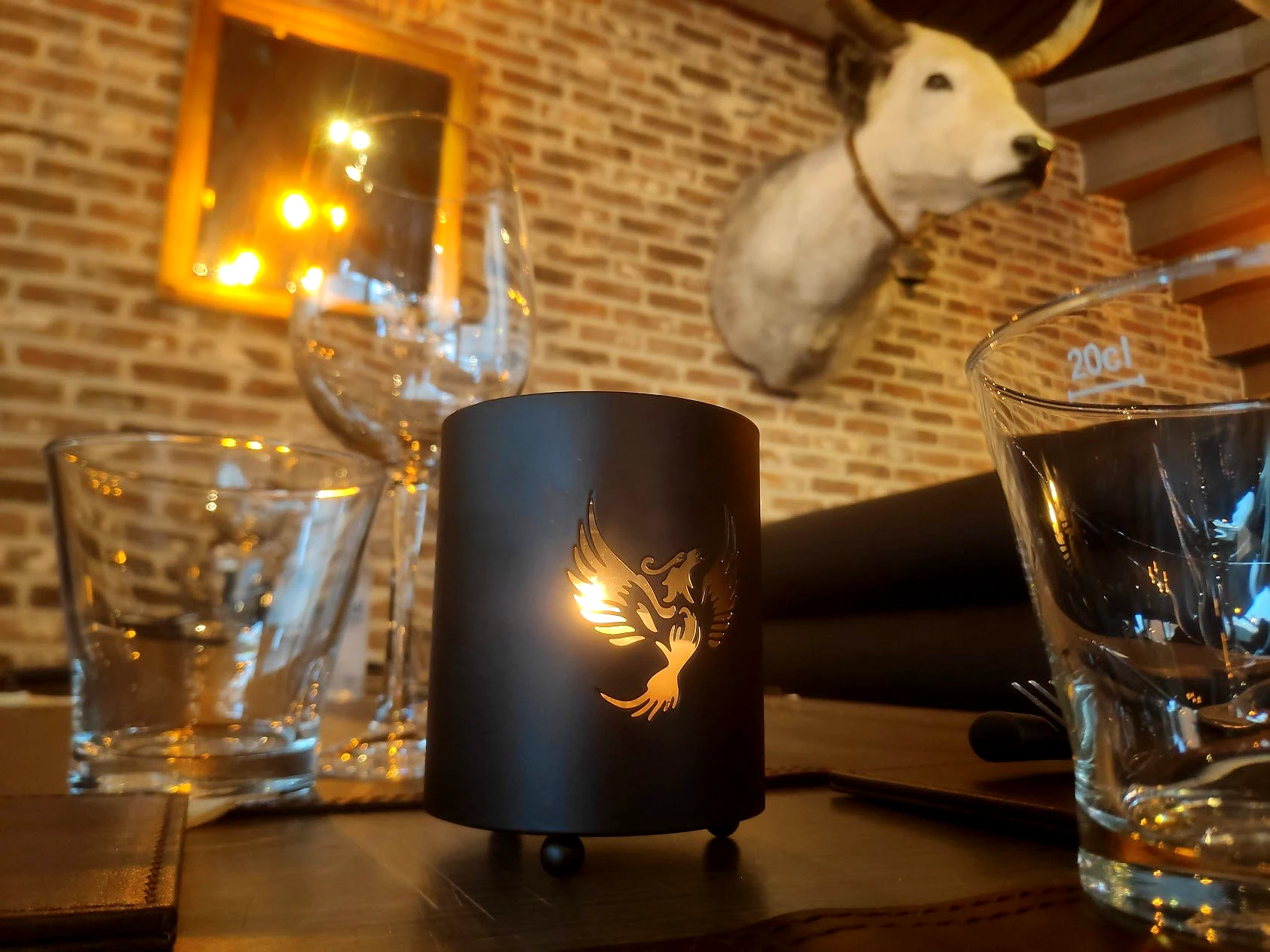 Phoenix Garden-detail op tafel met kaars, glaswerk en het merklogo in het interieur.