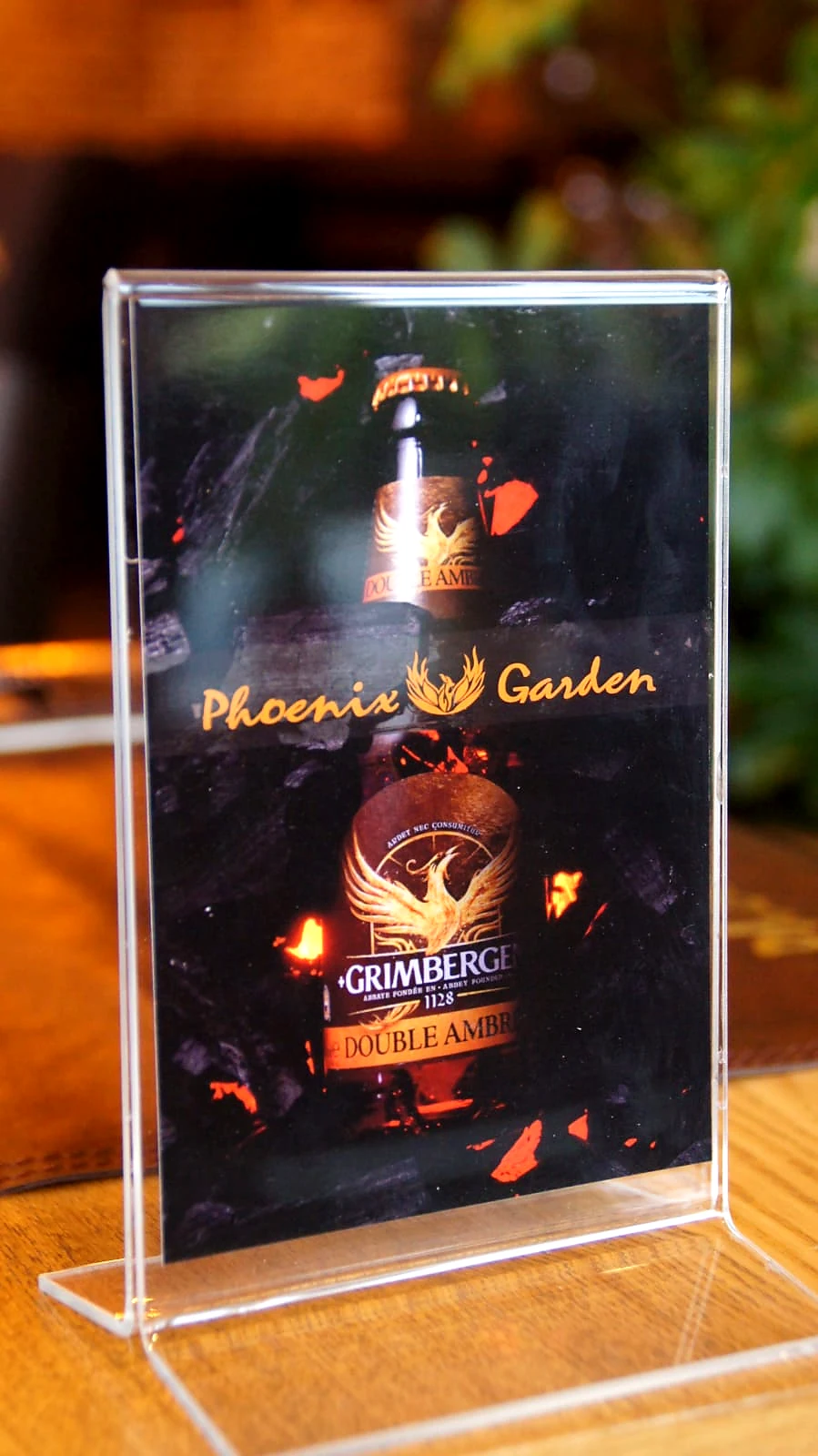 Phoenix Garden-tafelbord met Grimbergen Double Ambrée en het gouden restaurantlogo.