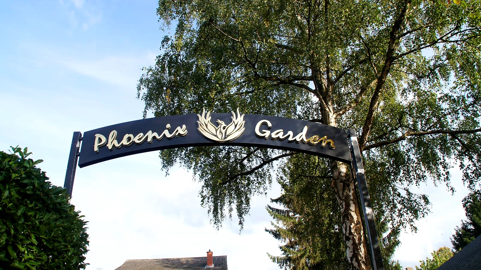 Volledige gouden Phoenix Garden-signing in de maatwerkpoort bij de parkeerplaats.