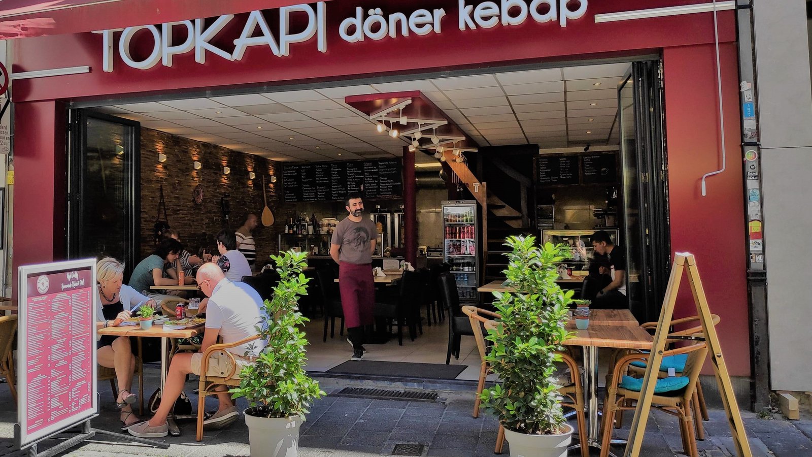 Open gevel van Topkapi döner kebab met terras, gasten en zicht op de zaak.