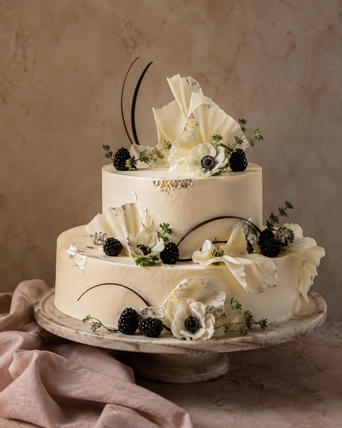 Elegante avondhuwelijkstaart met witte chocoladegolven, bramen en witte anemonen.